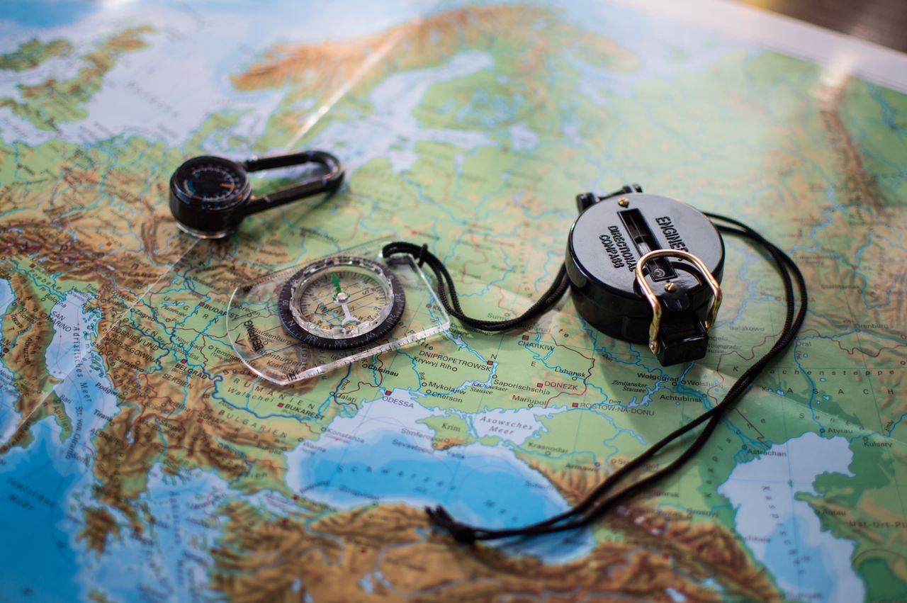 Flat lay of a European map with two compasses, symbolizing travel and exploration.